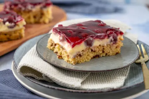 Ein Stück saftige Kirschtorte mit Pudding und Kirschen, bedeckt mit rotem Tortenguss.
