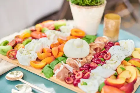 Antipasti-Platte mit Kerze, Wurst, Käse, Oliven und Brot auf Holztisch.
