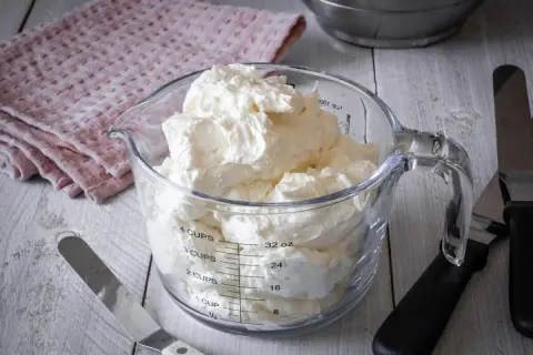 Ein Messbecher gefüllt mit luftiger Swiss Meringue Buttercreme, bereit für süße Kreationen.