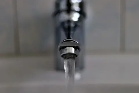 Strumień wody wypływa z chromowanego kranu. To właśnie dzięki niemu woda staje się miękka i przyjemna w dotyku.