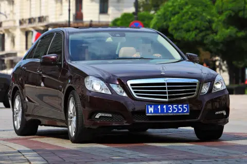 Ciemnobrązowy Mercedes z tablicą W 113555, wskazującą na rejestracje dyplomatyczne.