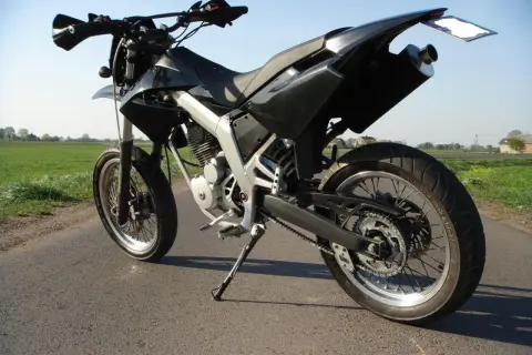 Czarny motocykl typu supermoto, gotowy do jazdy po wiejskich drogach. Senda czeka na przygodę.