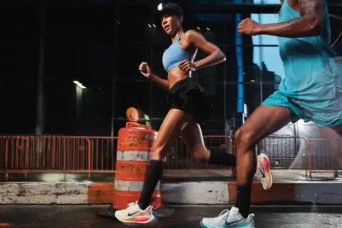 Coppia di runner notturni in città, impegnati in esercizi per migliorare la corsa. Le luci urbane illuminano la loro determinazione.