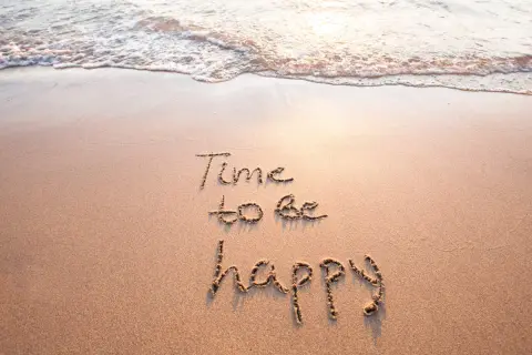 Sand mit Wellen und der Aufschrift "Time to be happy". Ein Moment des selig seins.