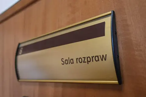 Tabliczka "Sala rozpraw" na drewnianych drzwiach. Może tu pracować referendarz sądowy.