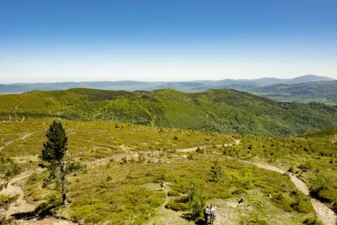 Malownicze szlaki na Baraniej Górze wiodą przez zielone wzgórza. Dwie osoby podziwiają krajobraz.