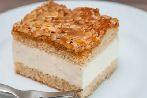 Ein Stück Bienenstich-Kuchen mit cremiger Füllung und karamellisierten Mandeln. Ein köstliches Rezept für Genießer.