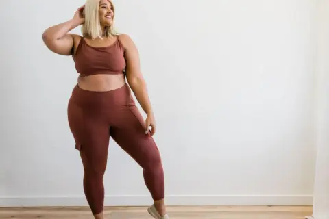 Kobieta plus size w brązowym komplecie sportowym, legginsy z kieszeniami.