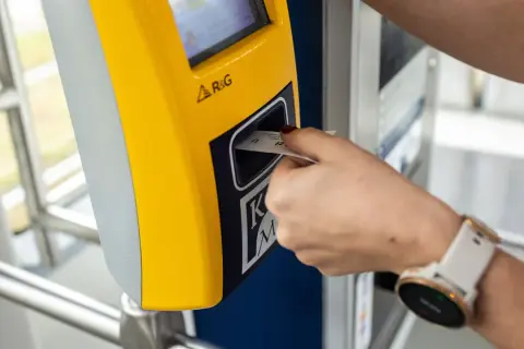 Wkładanie biletu dobowego Kraków do żółtego automatu.