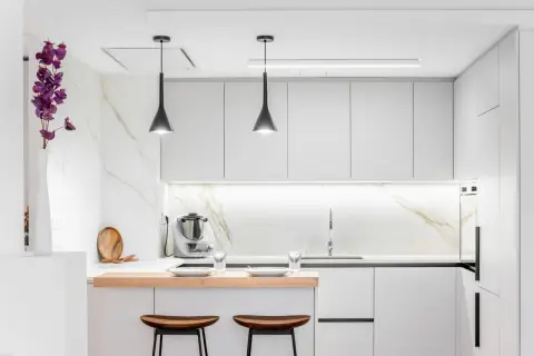 Cocina moderna y funcional, ideal para reformas de cocinas pequeñas. Muebles blancos, encimera de madera y detalles en mármol.