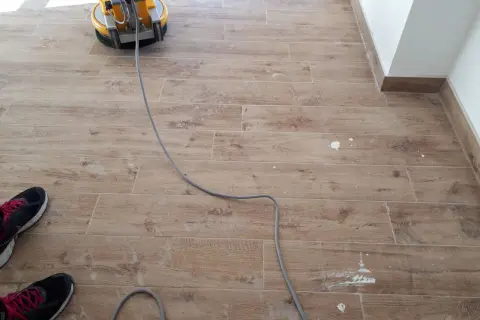 Macchina lucidatrice in azione per rimuovere la patina bianca sul pavimento in gres effetto legno.
