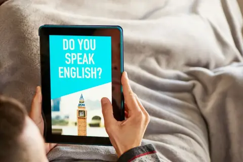 Osoba korzysta z tabletu z napisem "DO YOU SPEAK ENGLISH?", szukając darmowych narzędzi AI do nauki angielskiego.