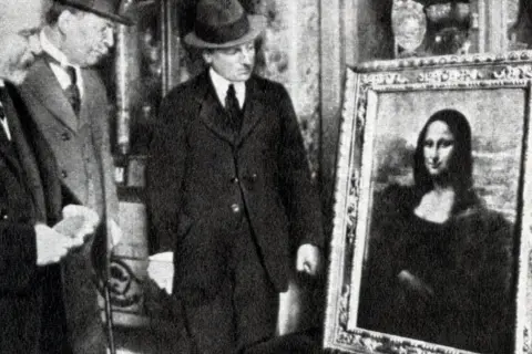 Mona Lisa skradziona! Obraz powrócił po kradzieży, a mężczyźni w garniturach oglądają go z uwagą.