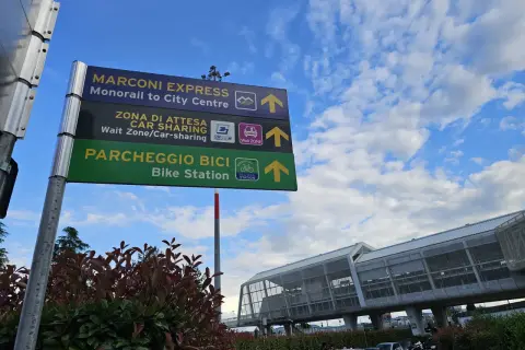 Znaki kierunkowe na lotnisku Bolonia: Marconi Express, Car Sharing i Bike Station.