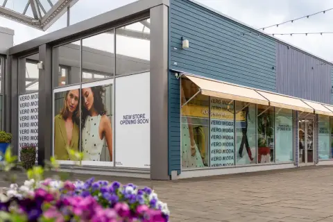 Vero Moda outlet med skyltar som visar "New Store Opening Soon". Blommor i förgrunden.