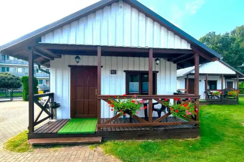 Urocze domki letniskowe Amber House z werandą i kwitnącymi pelargoniami. Idealne miejsce na wypoczynek.