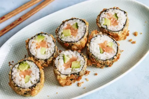 Knuspriges Tempura Sushi mit Lachs und Avocado auf einem Teller, bereit zum Genießen.