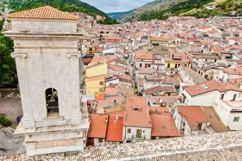 Vista dall'alto di San Marco in Lamis: un campanile in pietra domina un dedalo di tetti rossi e case arroccate tra le colline. Cosa vedere in questo borgo?
