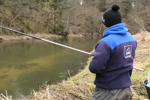 Łowienie z powierzchni na twardy chleb. Jak nie płoszyć kleni i jazi? Wędkarz z wędką nad rzeką.