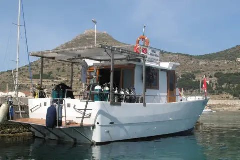 Barca da sub con bombole pronte per il battesimo dello scafo. Sullo sfondo, un castello su una collina.