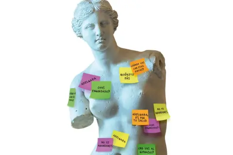 Estatuas clásicas cubiertas de notas adhesivas con mensajes sobre los **canones de belleza** y la presión por adelgazar.