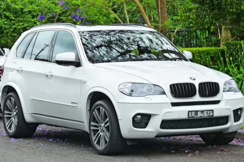 Białe BMW X5 na tle zieleni. Wiele osób szuka bmw x5 opinie przed zakupem.