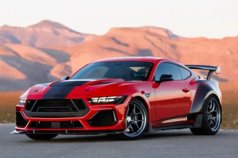 Czerwony Ford Shelby z czarnymi pasami i spojlerem na tle pustynnych gór.
