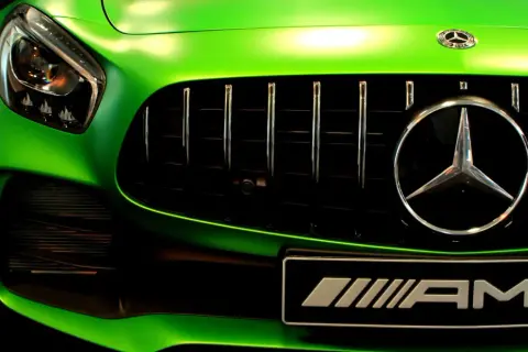 Zielony Mercedes AMG z błyszczącym chromem na grillu i emblematach.