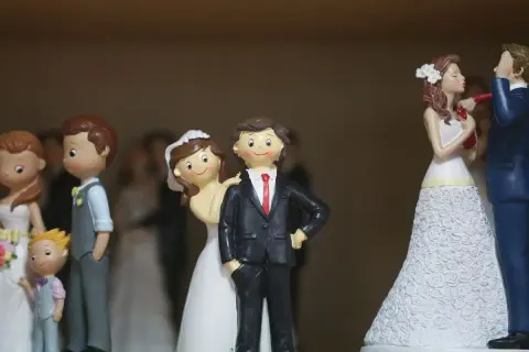 Figurines de couples mariés, certaines avec des enfants, sur un fond flou.