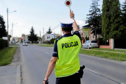 Policjant zatrzymuje ruch, by ukarać kierowcę za przekroczenie prędkości o 30 w terenie zabudowanym.