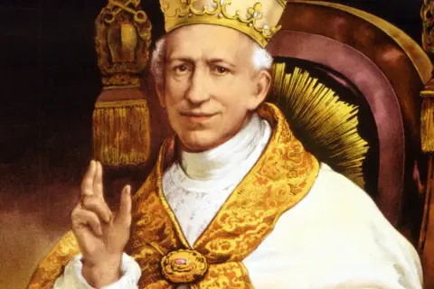 Portret papieża Leona XIII w bogatych szatach i tiarze, błogosławiący gestem dłoni.