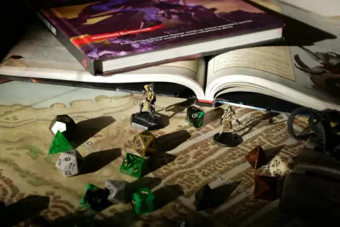 Księga D&D, kostki i figurki na mapie – wszystko gotowe na epickie gry RPG.