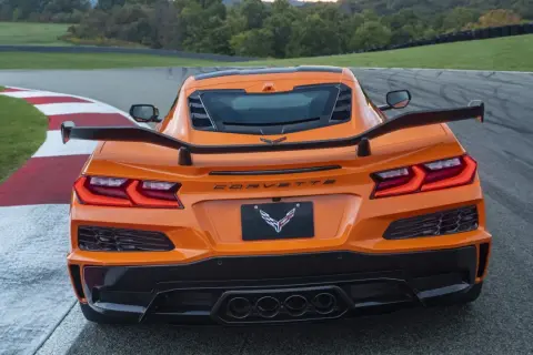 Pomarańczowy Corvette C9 z dużym spojlerem na torze wyścigowym.