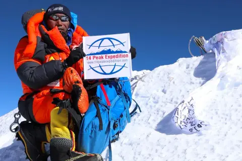 Kami Rita feiert auf dem Gipfel mit einem Schild der "14 Peak Expedition".