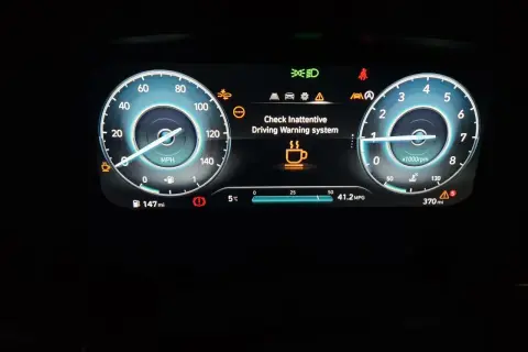 Panel de Hyundai i20 con fallo: "Check Inattentive Driving Warning system" y taza de café.