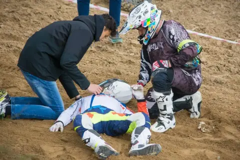 Po wypadku Tomasza Golloba, ratownicy udzielają pomocy leżącemu na piasku zawodnikowi w stroju motocyklowym.