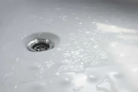 Acqua che scorre nello scarico della doccia, un segno che la pulizia è stata efficace.