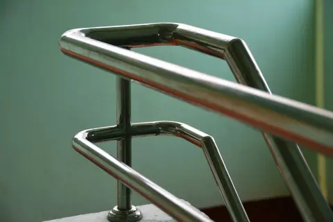 Precyzyjne gięcie rur stalowych na poręczy schodowej. Połyskujący metal tworzy elegancką formę.