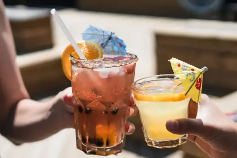 Dwa orzeźwiające drinki, jeden różowy z owocami i pomarańczą, drugi żółty z plasterkiem cytrusa. Idealne na letnie popołudnie, może z dodatkiem białego wina.