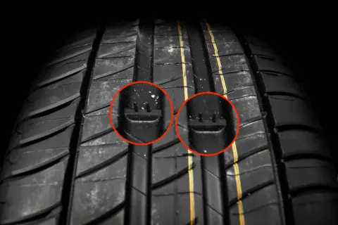 Gros plan sur un pneu de voiture, avec deux cercles rouges mettant en évidence les indicateurs d'usure. C'est un bon indice pour savoir quand changer ses pneus.