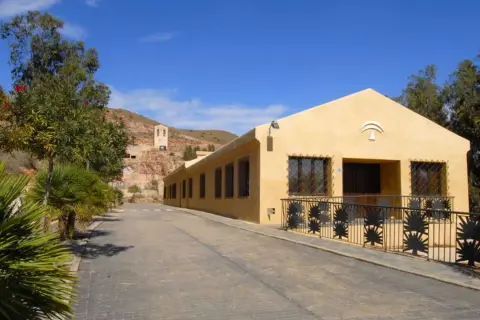 La casa de los volcanes, un edificio amarillo con rejas de palmeras, se alza bajo un cielo azul.