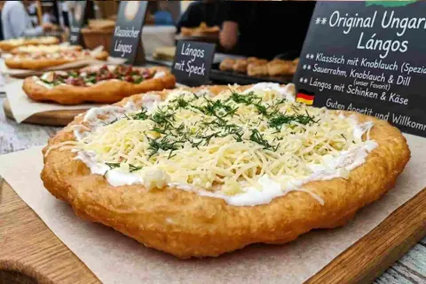 Frisch frittierter Lángos-Teig, belegt mit Sauerrahm, geriebenem Käse und Dill. Daneben weitere Lángos-Varianten.