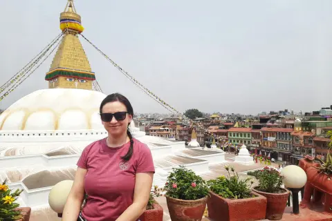 Kobieta w okularach przeciwsłonecznych pozuje na tle stupy Bodnath w Nepalu. Marzenie o lotach do Nepalu spełnione!