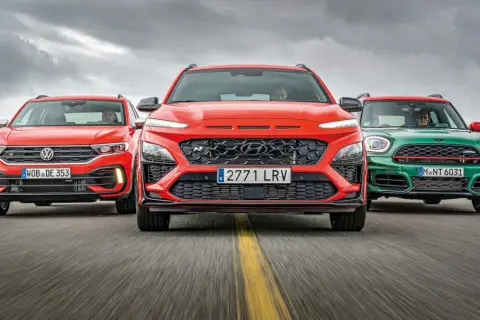 Trzy sportowe małe SUV-y: czerwony Volkswagen, pomarańczowy Hyundai i zielony Mini, jadące po drodze.