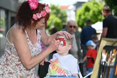 Kind wird beim Stadtfest in Radevormwald von einer Frau mit Spiderman-Maske bemalt.