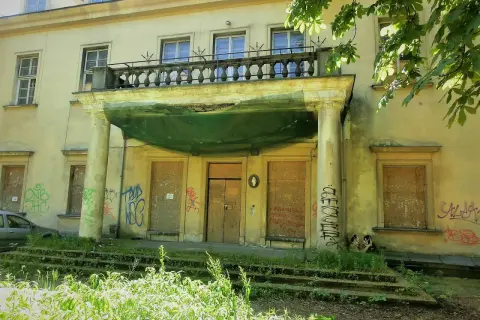 Zaniedbany pałac Tarnowskich w Krakowie, z zabitymi deskami oknami i drzwiami, pokryty graffiti.