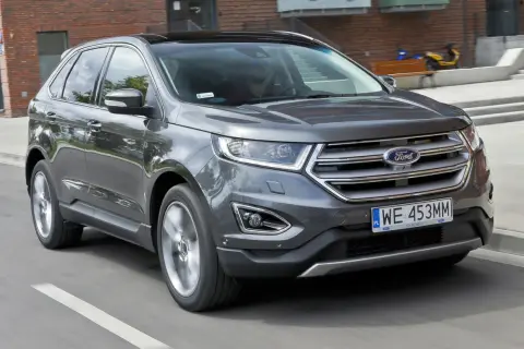 Szary Ford Edge w ruchu miejskim. Kierowca zadowolony, co potwierdzają pozytywne ford edge opinie.