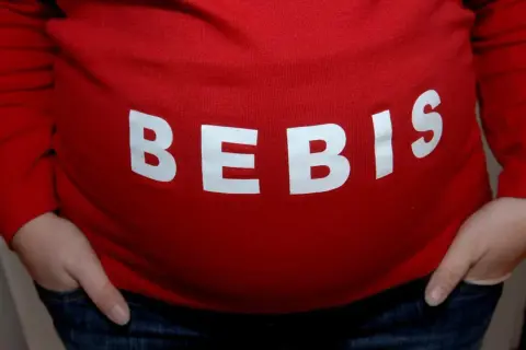 Gravid mage med texten "BEBIS". Viktigt att undvika alkohol tidig graviditet för bebisens skull.