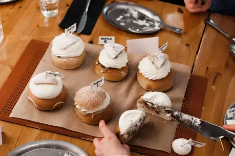 En härlig samling semlor med fluffig grädde och flaggor. En semla är uppskuren, redo för en smak av ritorno semla.