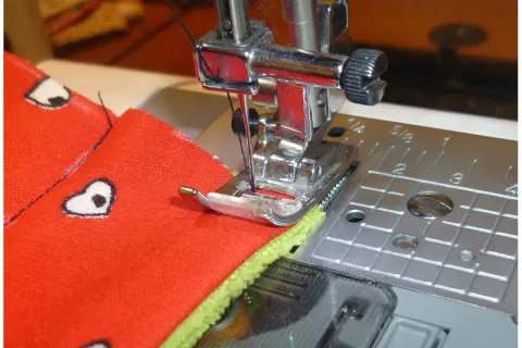 Jak ustawić maszynę do szycia: igła schodzi w materiał, przygotowując go do ściegu.